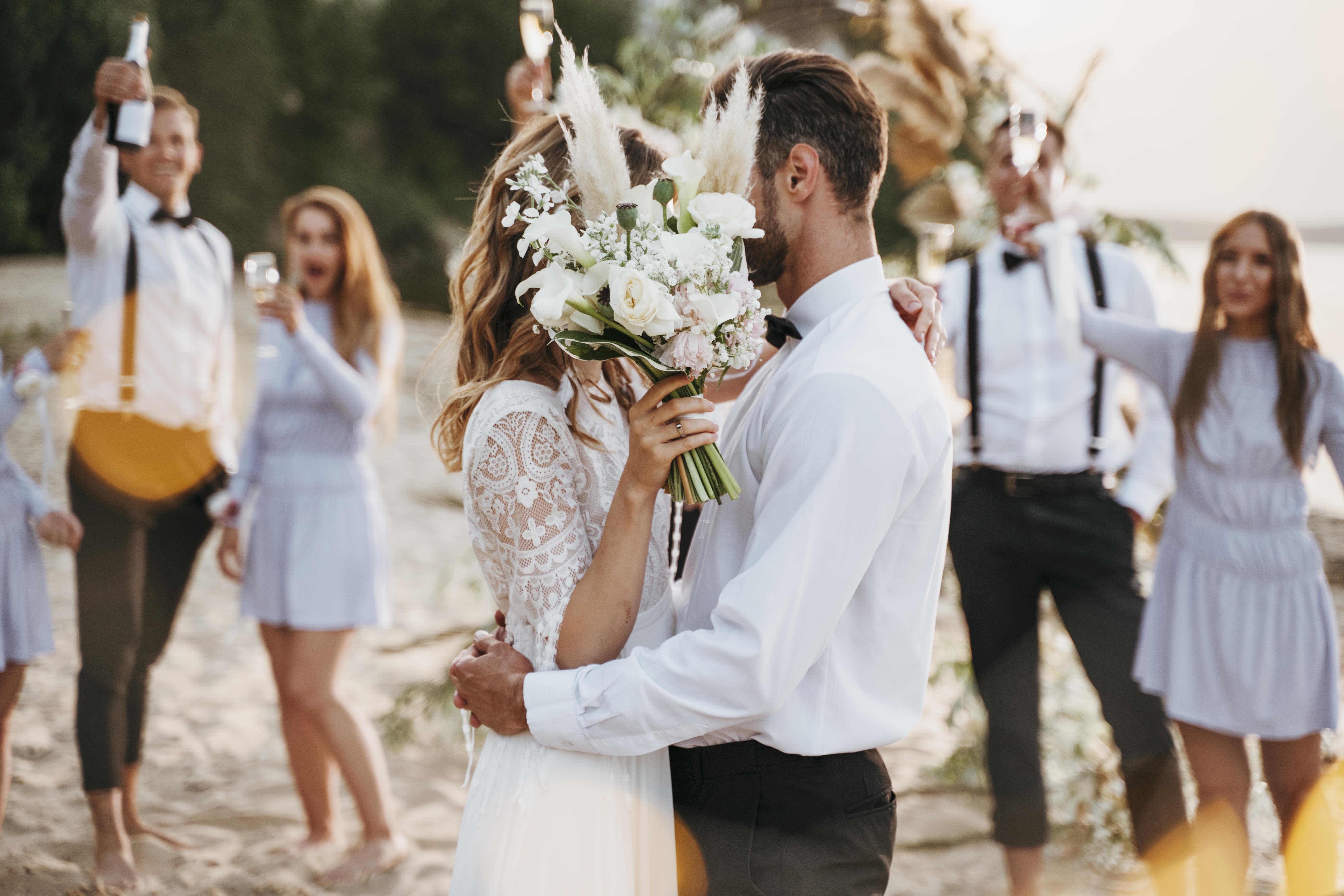braut-und-brautigam-haben-ihre-hochzeit-mit-gasten-am-strand-min